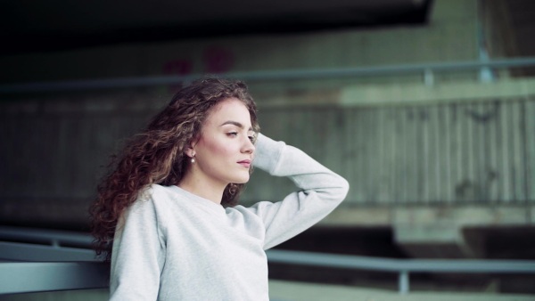 Beautiful young woman standing under the bridge in the city. Slow motion.