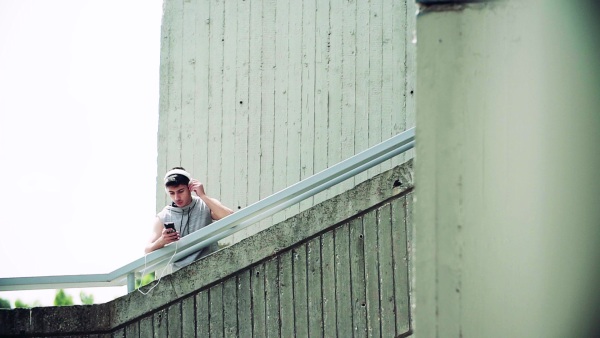 Young sporty man with smartphone and headphones in the city, listening to music. Copy space. Slow motion.