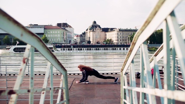 Beautiful young woman stretching on the bridge in the city. Slow motion.