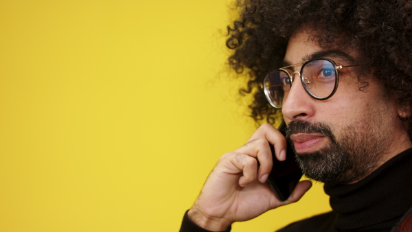 Portrait of cheerful mature man with smartphone in a studio on yellow background.