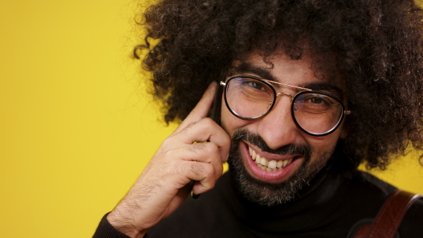 Close up of cheerful mature man with smartphone in a studio on yellow background.