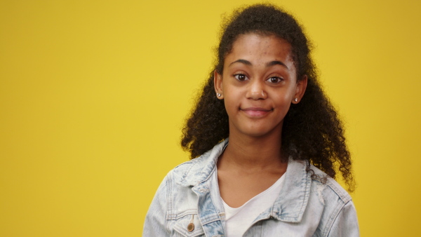 Teenager girl in a studio on yellow background looking at camera. Copy space.