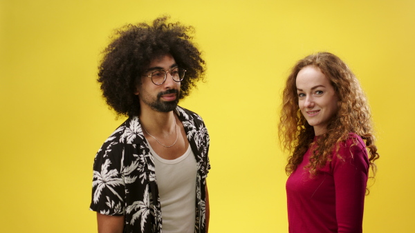 Portrait of mature man and young woman in a studio on yellow background, giving high five.