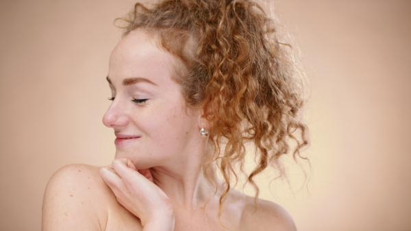 Portrait of topless young woman in a studio looking at camera, beauty concept.