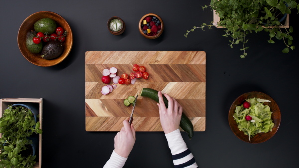 Top view of unrecognizable young woman making a vegetable salad.