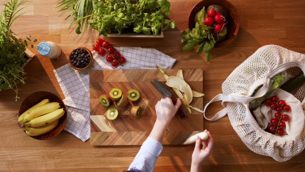 Top view of unrecognizable young woman slicing a fruits.