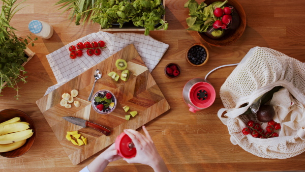 Top view of unrecognizable young woman making a smoothie.