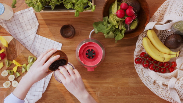 Top view of unrecognizable young woman making a smoothie.