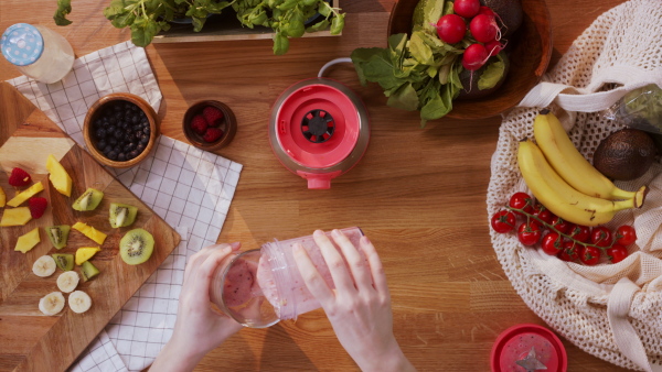 Top view of unrecognizable young woman making a smoothie.