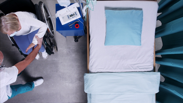 Top view of doctor pushing patient in wheechair in hospital. Copy space.