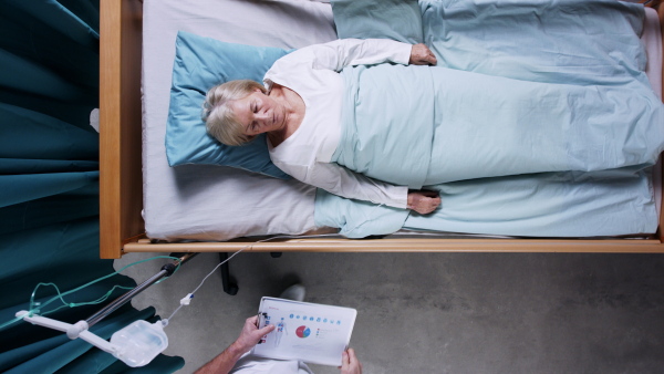 A top view of doctor and woman patient with iv drip in bed in hospital.