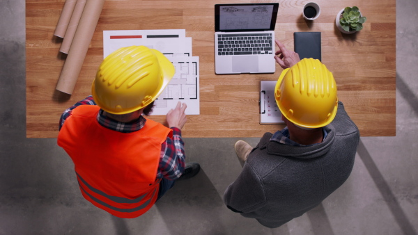 Top view of two architects in hard hats closing a deal. Copy space.