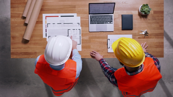 Top view of two architects in hardhats discussing about project. Copy space.