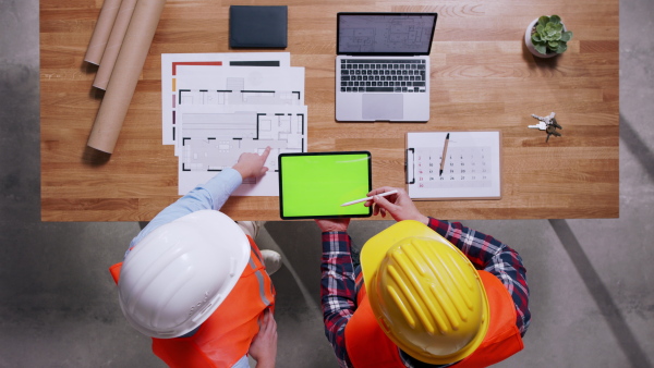 Top view of two architects with tablet in hardhats discussing about project. Copy space.