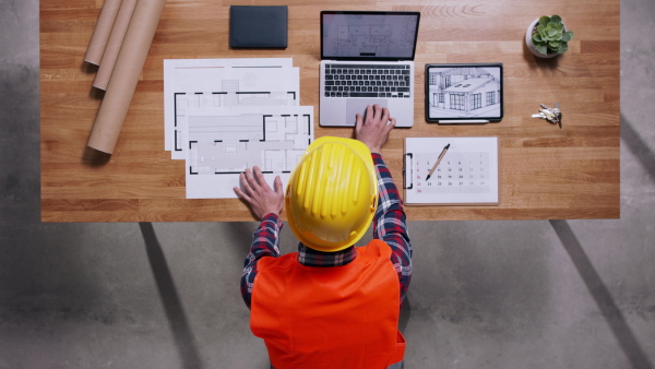 Top view of architect in hardhat working on a housing project. Copy space.