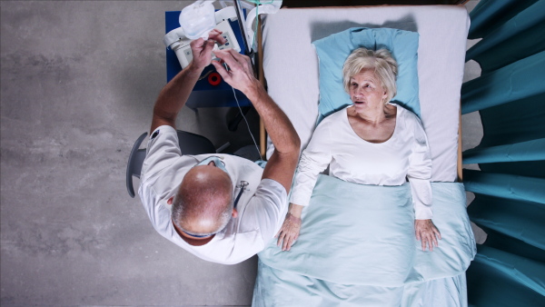 A top view of doctor with stethoscope examining patient in bed in hospital. Copy space.