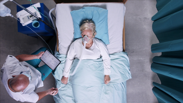 A top view of doctors with stethoscope examining patient in bed in hospital. Copy space.