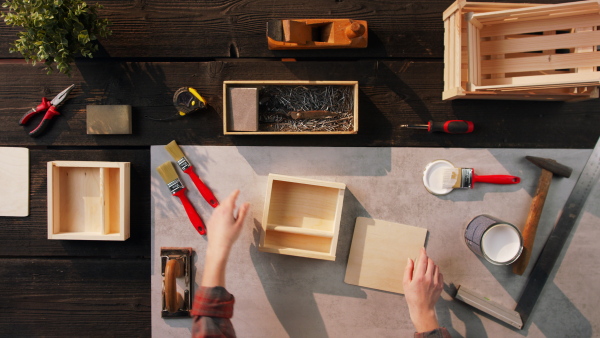 A top view of unrecognizable woman making wooden boxes, small business and desktop concept.