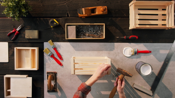 A top view of unrecognizable woman making wooden boxes, small business and desktop concept.