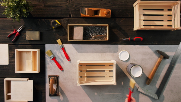 A top view of unrecognizable woman making wooden boxes, small business and desktop concept.