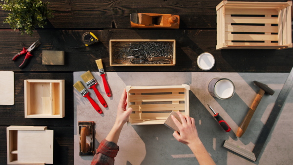 A top view of unrecognizable woman making wooden boxes, small business and desktop concept.