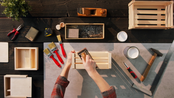 A top view of unrecognizable woman making wooden boxes, small business and desktop concept.