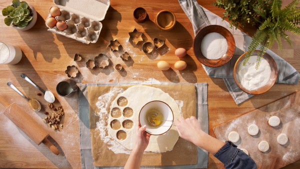 A top view of unrecognizable woman baking biscuits, desktop concept.