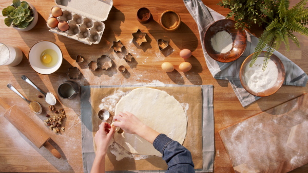 A top view of unrecognizable woman baking biscuits, desktop concept.