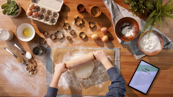 A top view of unrecognizable woman baking biscuits, desktop concept.