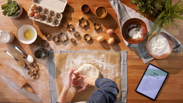 A top view of unrecognizable woman baking biscuits, desktop concept.