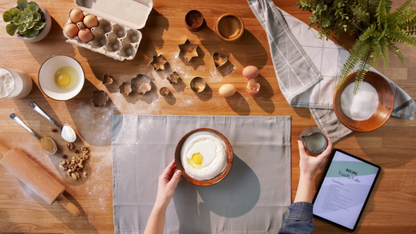 A top view of unrecognizable woman baking biscuits, desktop concept.