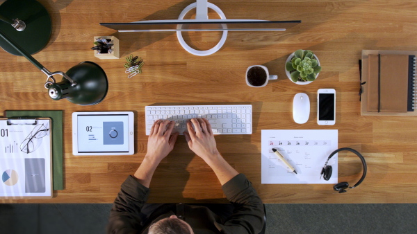 A top view of businessman working on computer at desk in home office.