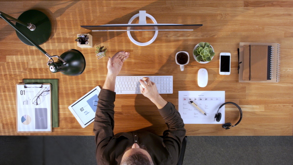 A top view of businessman working at desk and disinfecting hands in home office. Coronavirus concept.