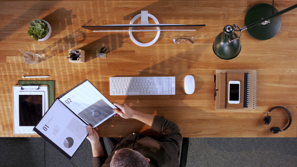 A top view of businessman working on computer at desk in home office.