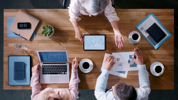 Top view of colleagues businesspeople working on computer at desk with paperwork in home office.