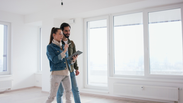 Happy young couple with tablet moving and planning in new flat, new home and relocation concept.