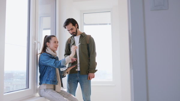 Happy young couple with tablet moving and planning in new flat, new home and relocation concept.