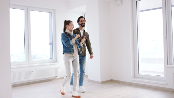 Happy young couple with tablet moving and planning in new flat, new home and relocation concept.