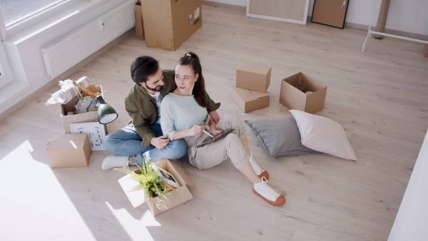 Happy young couple with tablet moving and planning in new flat, new home and relocation concept.