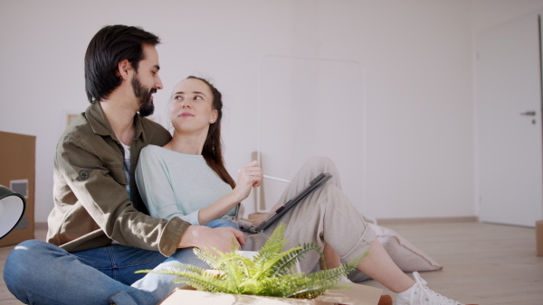 Side view of happy young couple with tablet moving and planning in new flat, new home and relocation concept.