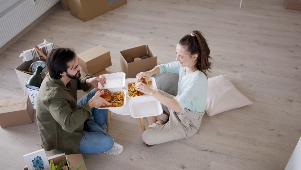 Top view of young couple with hamburgers and boxes moving in new flat, new home and relocation concept.