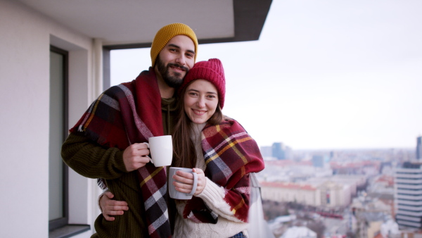 Happy young couple owners with coffee on balcony in new flat, moving in, new home and relocation concept.