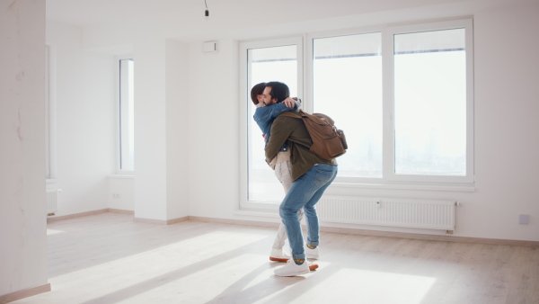 Happy young couple owners hugging in new flat, moving in, new home and relocation concept.