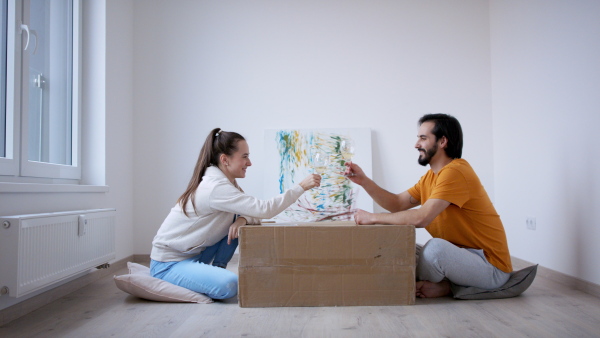 Happy young couple with wine moving in new flat, new home and relocation concept.