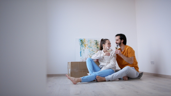 Happy young couple with wine moving in new flat, new home and relocation concept.