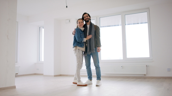 Happy young couple owners in new flat, moving in, looking at camera. New home and relocation concept.