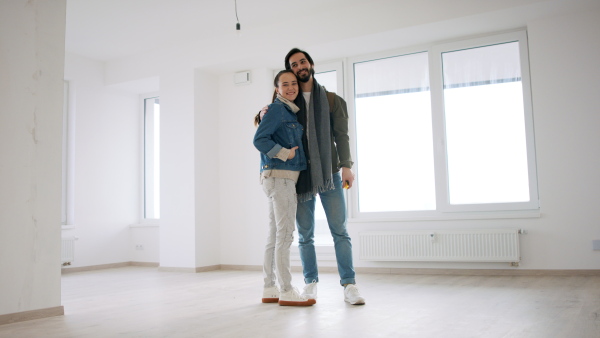 Happy young couple owners in new flat, moving in, looking at camera. New home and relocation concept.