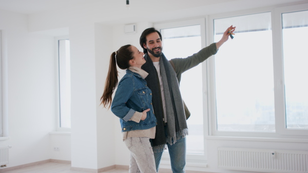 Happy young couple owners in new flat, moving in, looking at camera. New home and relocation concept.