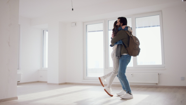 Happy young couple owners hugging in new flat, moving in, new home and relocation concept.