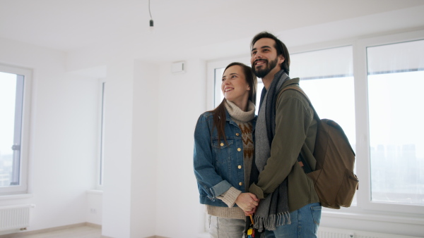 A young couple with keys moving in new flat, new home and relocation concept.